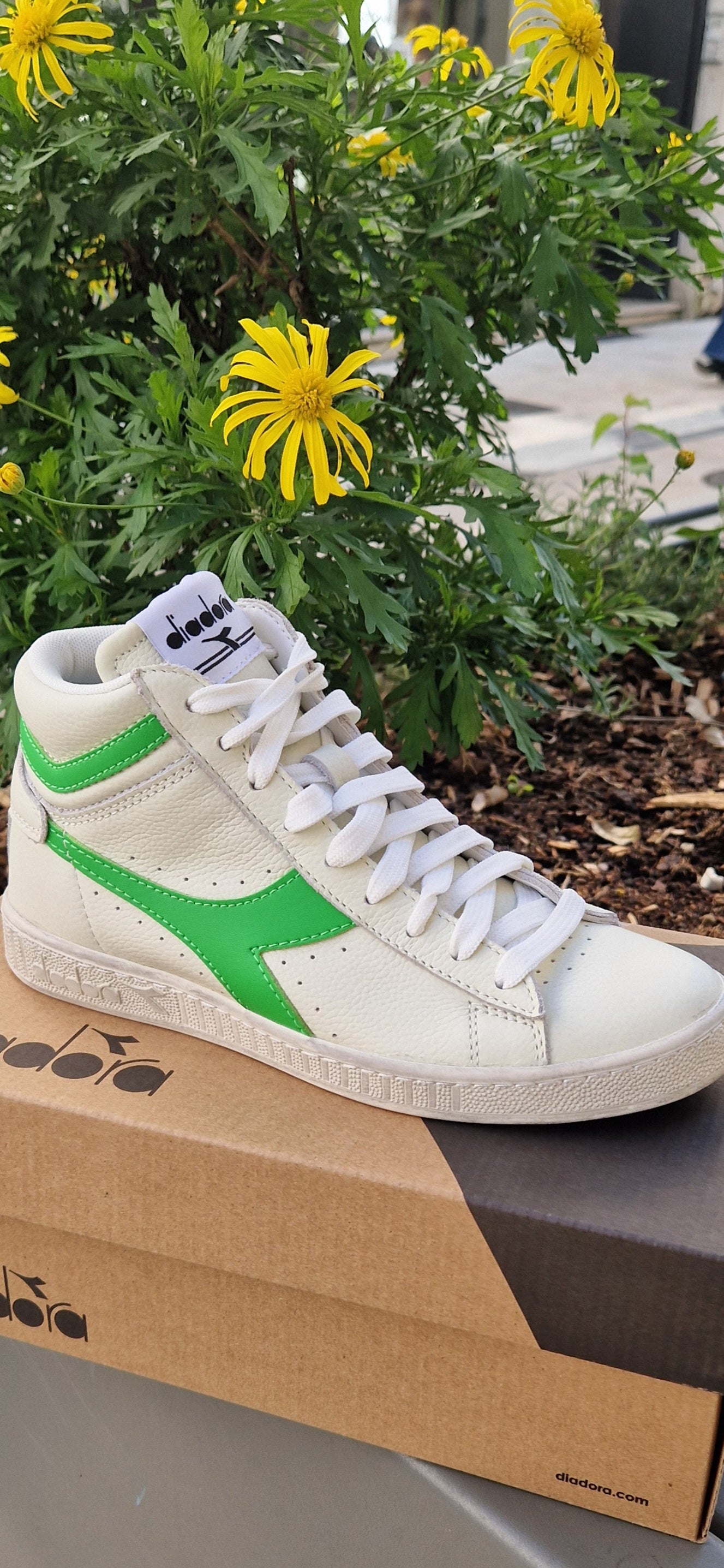 Basket Diadora modèle game L High vert fluo et blanche posée sur sa boîte Diadora.