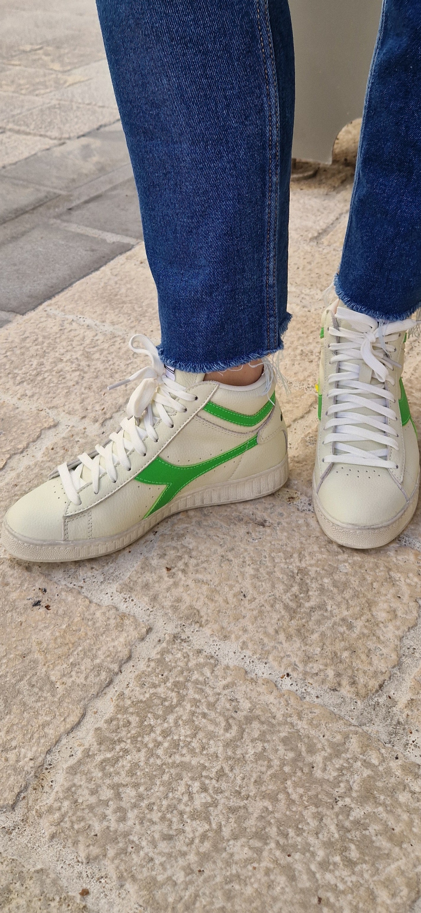 Baskets montantes Diadora Game L High, blanches avec logo vert fluo, portées.