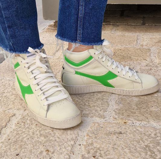 Vue latérale de la paire Game L High de chez Diadora portée, mettant en valeur le contraste vif du fluo et le cuir blanchi.