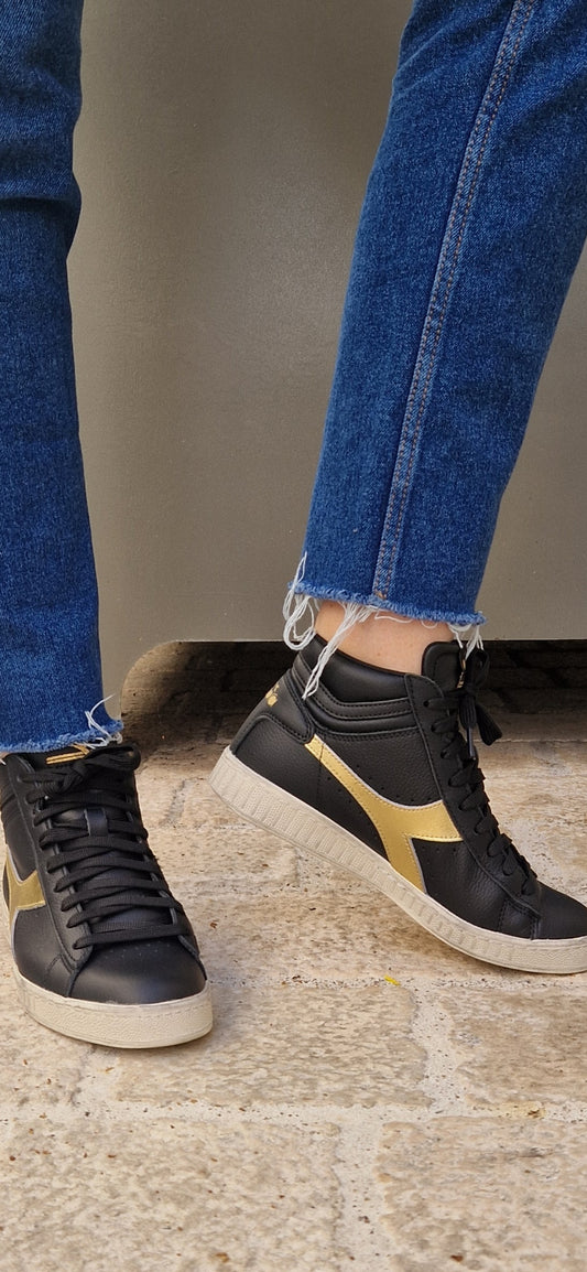 Baskets Diadora modèle Game L Hight portées. Vue de côté mettant en valeur la ligne montante et le contraste noir/or.