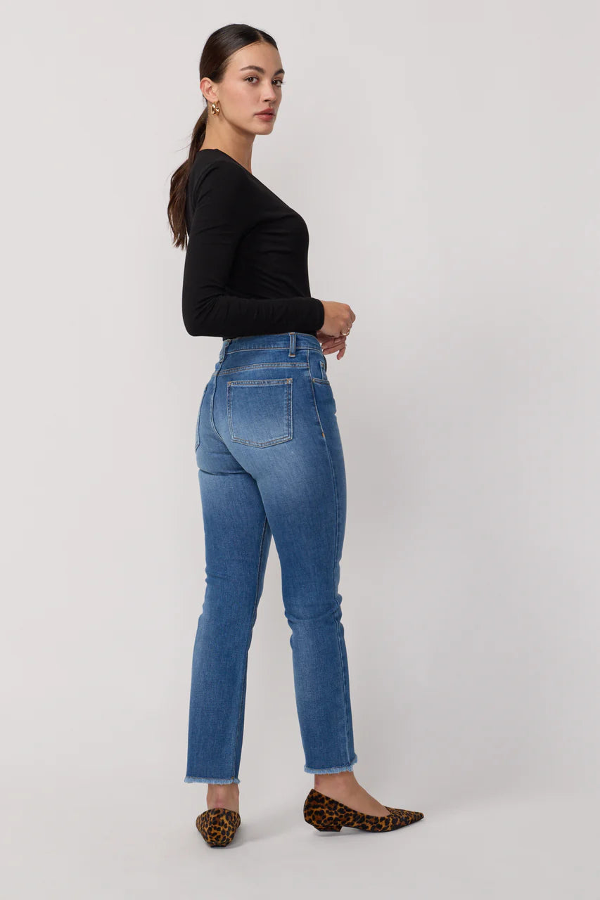 Jean Cara de la marque Acquaverde en denim bleu, porté de profil. Taille haute et finitions effilochées.