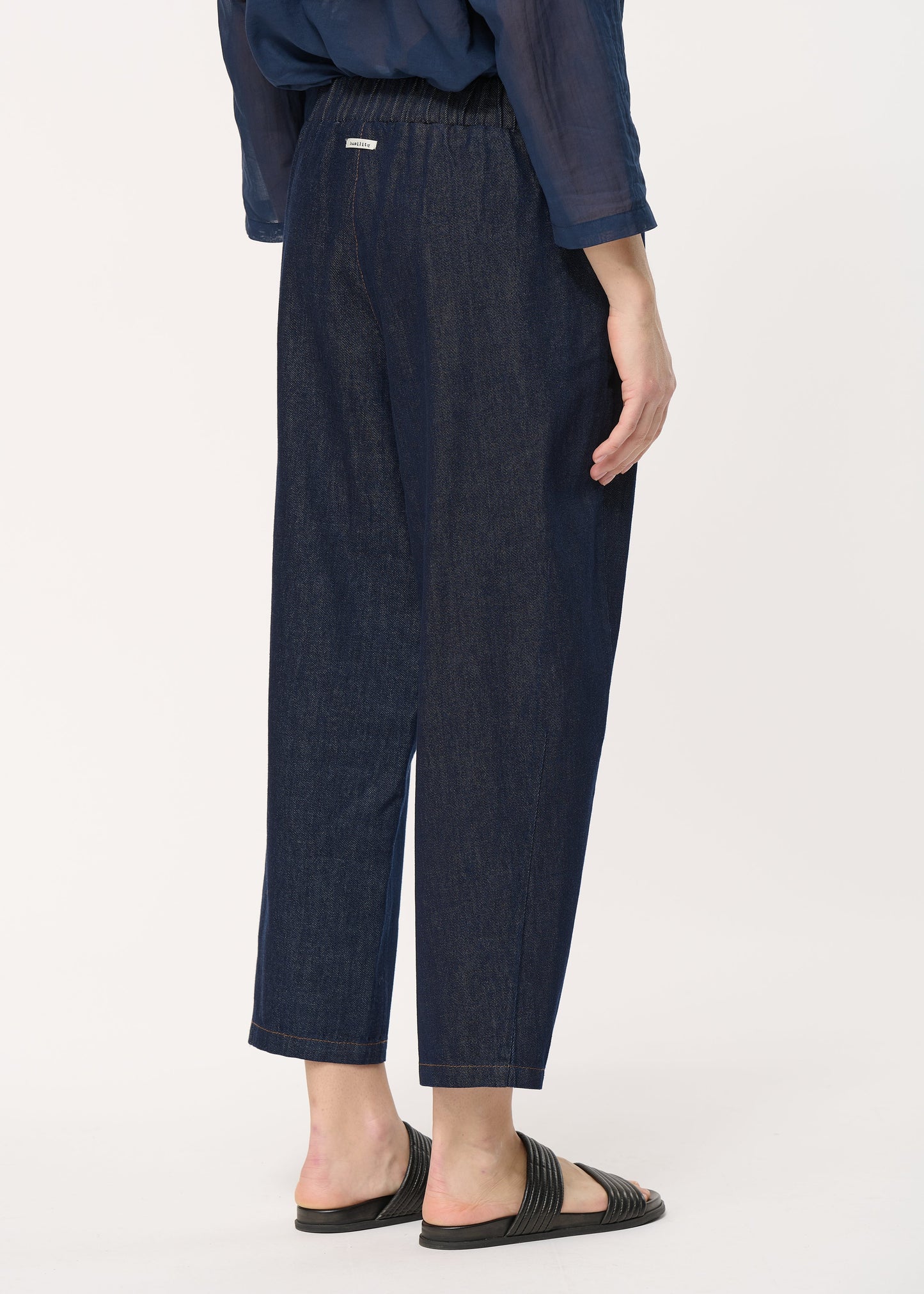 femme portant le pantalon unia en denim de chez humility, vue de dos.