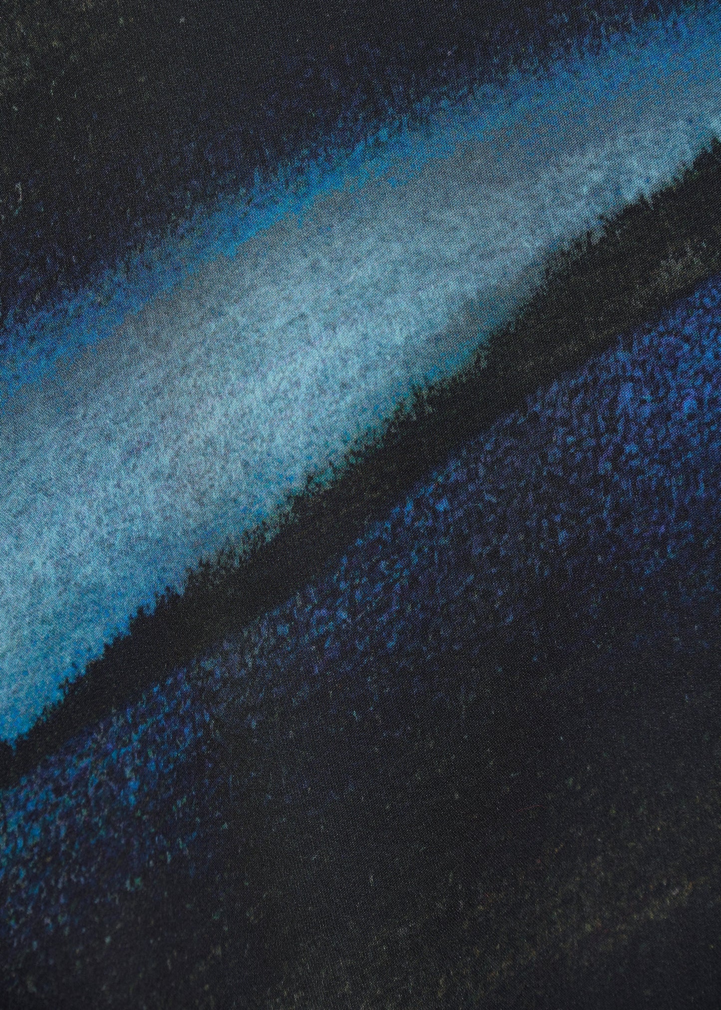 Gros plan sur l’imprimé artistique aux nuances de bleu, noir et turquoise de la robe Bachira de chez Humility.