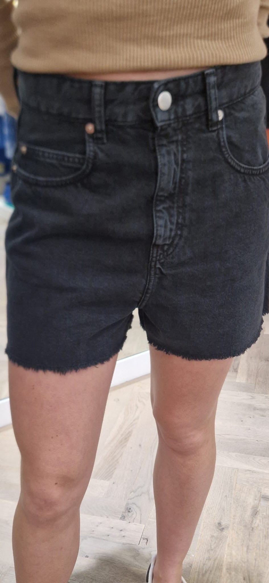 Short taille haute en jean noir de la marque Acquaverde, porté. Coupe droite, finitions effilées sur le bas.