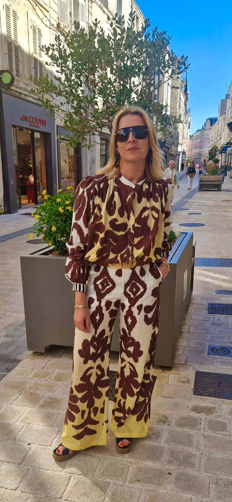 Femme portant le pantalon imprimé Imprévu , modèle shadow, dans une rue commerçante, vue de face.