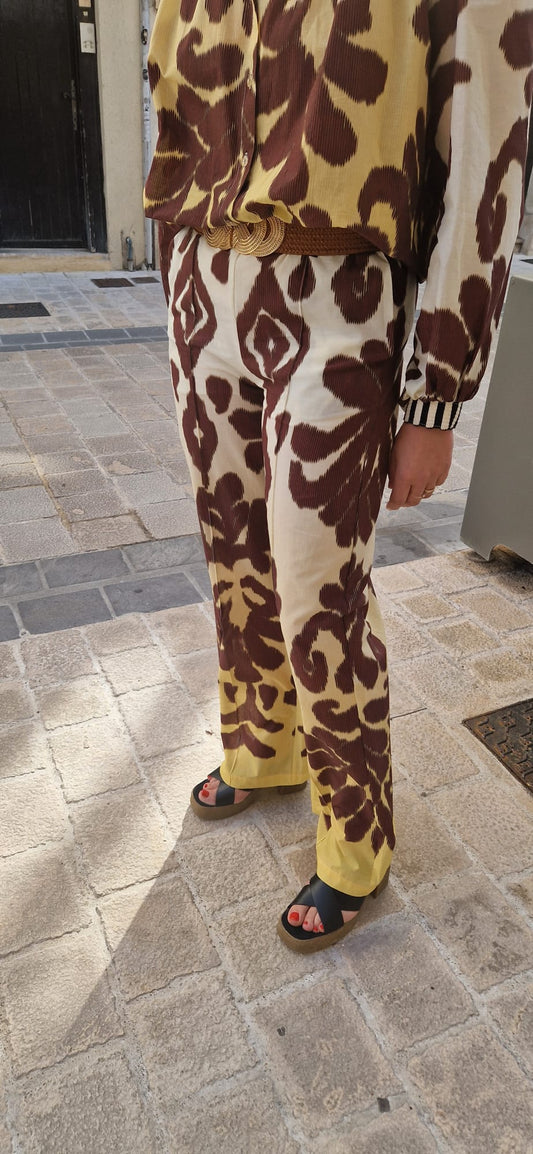Plan sur le bas du pantalon shadow de chez Imprévu avec les motifs graphiques bordeaux et jaune.
