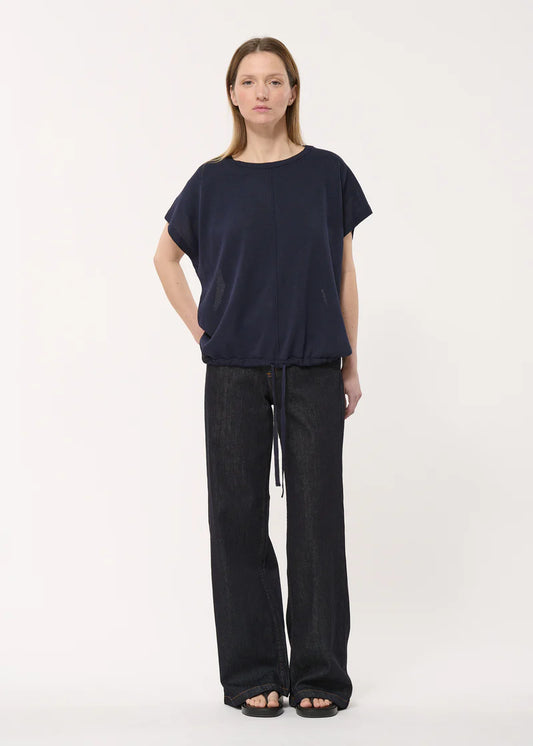 Pull sans manches Jio Humility, coupe ample avec lien ajustable à la taille, coloris bleu marine, porté avec un pantalon large.
