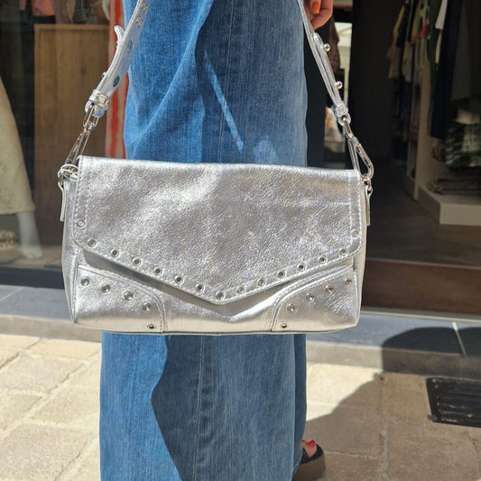 Sac Serena de la marque Neuville en cuir argenté porté à la main. Vue extérieure mettant en valeur la texture métallisée et les détails cloutés.