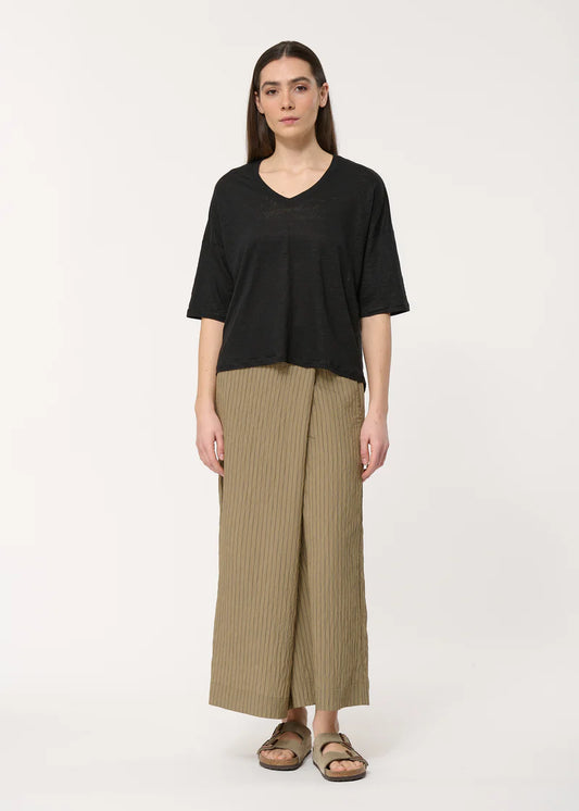 T-shirt Berlin Humility manches 3/4 en noir, col en V et coupe ample, porté avec une jupe culotte.
